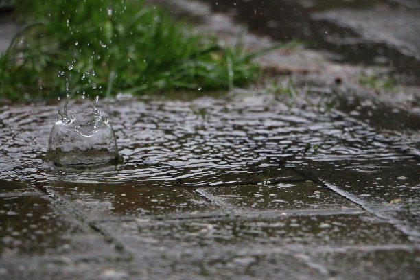 大雨在街上的水坑里溅起水花图片下载