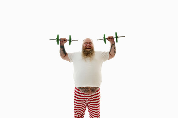 孤立的肖像，一个超重的大胡子男子与纹身的胳膊锻炼哑铃，并有乐趣地看着相机图片下载
