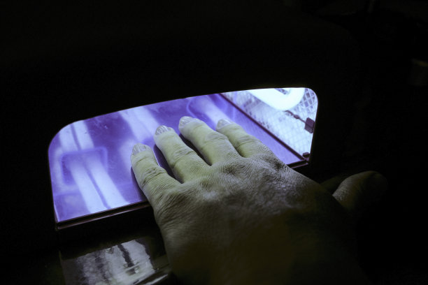 装置与紫外线灯。涂过漆的指甲在深色背景下的夜间干燥。图片下载