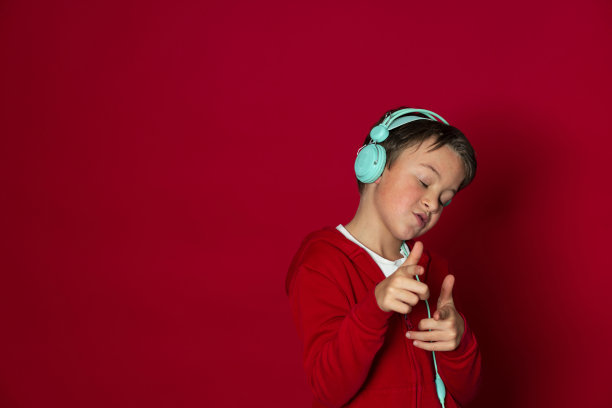 年轻帅气的学生戴着绿松石耳机，穿着红色毛衣图片下载