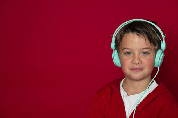 年轻帅气的学生戴着绿松石耳机，穿着红色毛衣图片下载