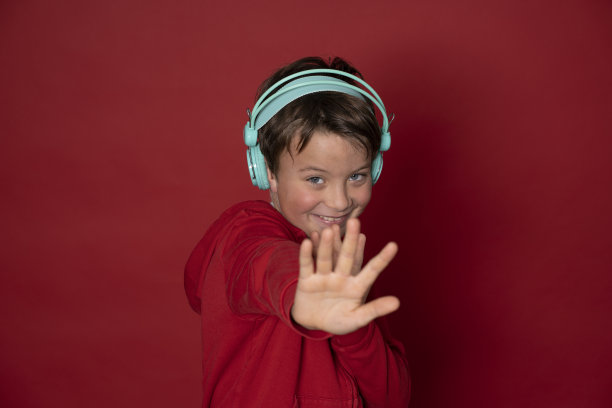 年轻帅气的学生戴着绿松石耳机，穿着红色毛衣图片下载