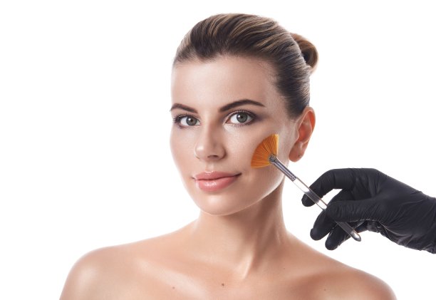 孤立的肖像在白色的背景上一个美丽的年轻女子和一只手在黑色手套手持刷子靠近她的脸。美容cocept图片下载