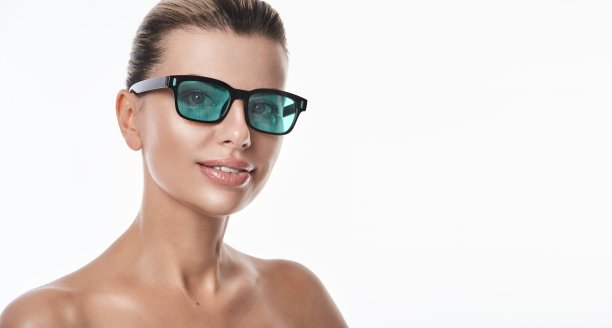 美丽的白种人微笑的女人在保护性的医疗眼镜，这是戴在美容激光程序。广告照片。光学。Ophtalmology图片下载