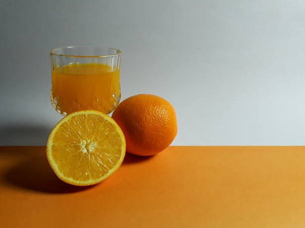 近距离观察整个和半熟的新鲜有机柑橘水果与玻璃上的橙色背景。图片下载