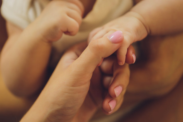 父母的手握住婴儿的手掌。图片下载