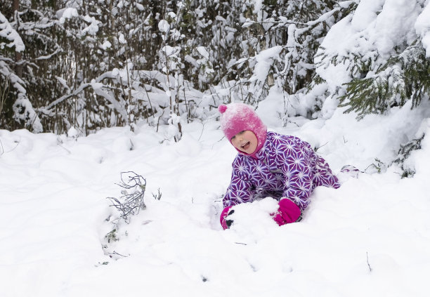 一个孩子，一个5岁的白人女孩，快乐地在深深的雪地里玩耍。图片下载