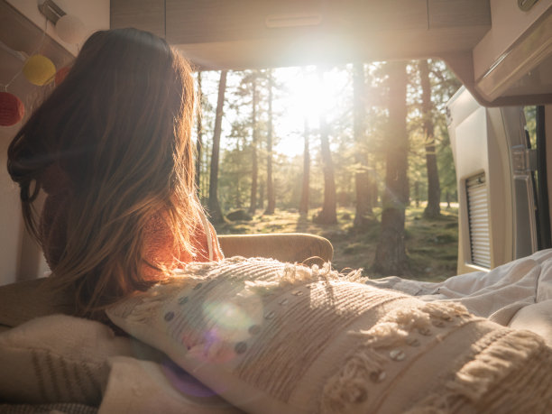 一个女人在她的货车后面放松，俯瞰日落时的森林图片下载