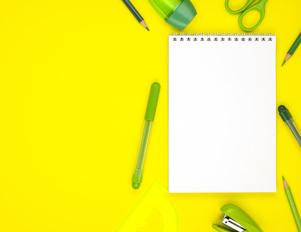白色空白记事本与绿色学校文具孤立在黄色背景，俯视图图片下载