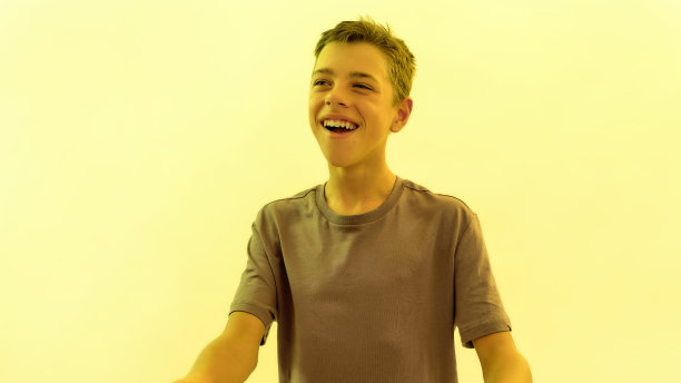 快乐的少年残疾男孩的肖像与脑瘫，而摆出孤立的黄色灯光背景微笑图片下载