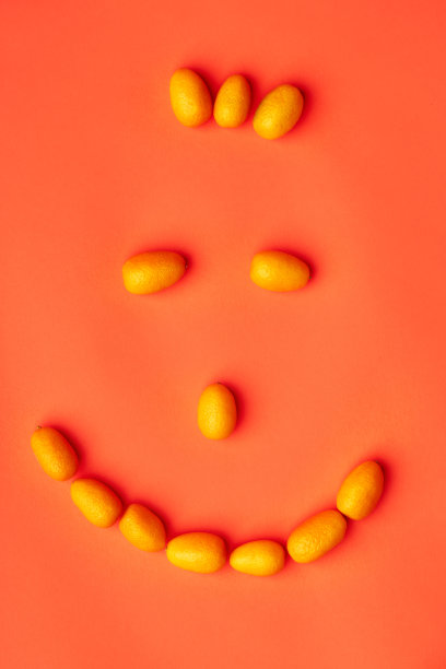 在工作室拍摄的橙红色背景上的金橘水果平躺脸图片下载