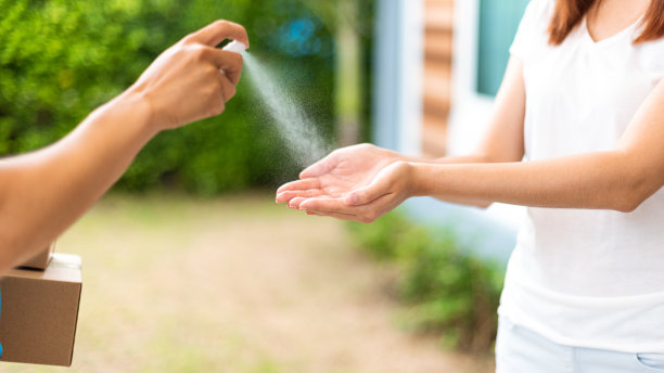 送餐员使用酒精洗手喷雾，以免感染传染病。素材图片