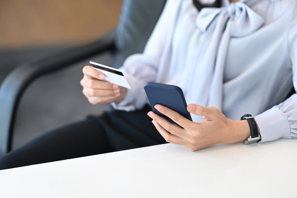 手持信用卡，用手机在线购物或进行金融交易的女性。图片下载