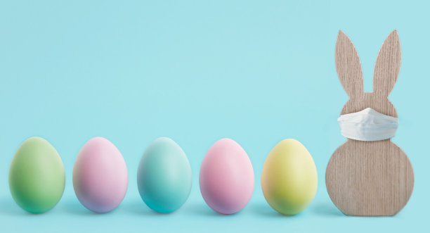 复活节横幅或镶边快乐。复活节假期的冠状病毒防护概念。带着保护面具和彩色彩蛋的复活节兔子。待在家里为Covid-19概念复活节时间提供拷贝空间。图片下载