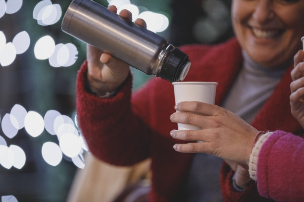 在一个冬天的晚上，当你在外面闲逛时，往杯子里倒一杯热饮图片下载