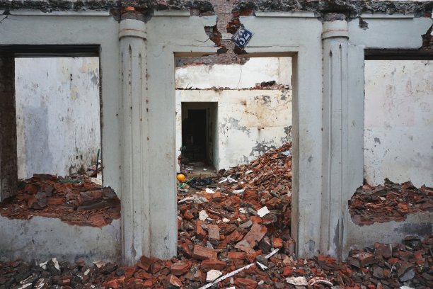 从空的窗框和门框可以看到部分被拆毁的建筑，里面有碎砖和瓦砾图片下载