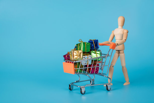 假日季促销概念。木制的人的照片，抱着篮子装满了闪亮的包装小礼物孤立的蓝色背景与广告空间图片下载