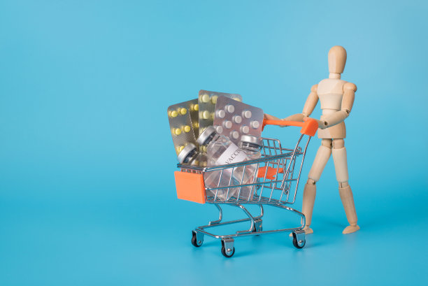 购买毒品的概念。照片中的木制男人扛着装满不同药物药丸的购物车孤立的蓝色背景图片下载