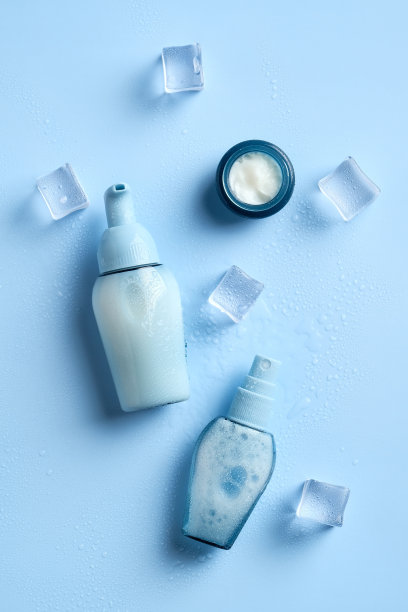 蓝色背景上的保湿化妆品和冰块。前视图。图片下载