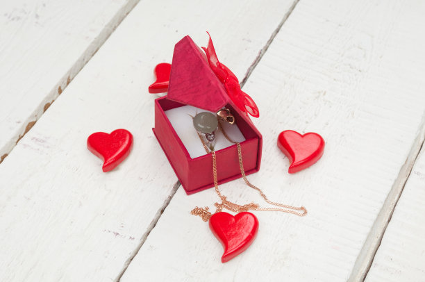 红色的心和盒子与戒指和金项链在木制的背景。情人节卡片图片下载