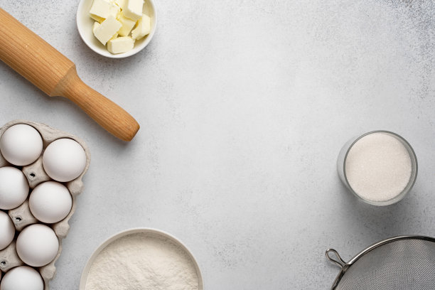 面粉，糖，筛子，擀面杖，黄油和白色鸡蛋在灰色的背景图片下载
