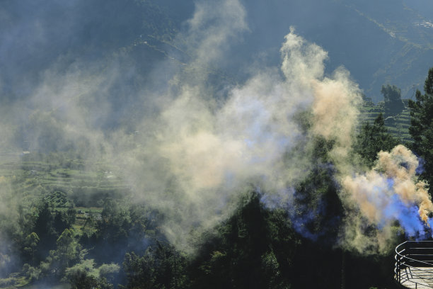 以自然为背景的橙色和蓝色的彩色烟雾。图片下载