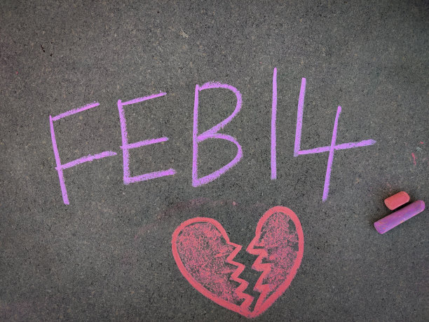 灰板上的题字文字，2月14日，带有令人心碎的符号。使用彩色粉笔。图片下载