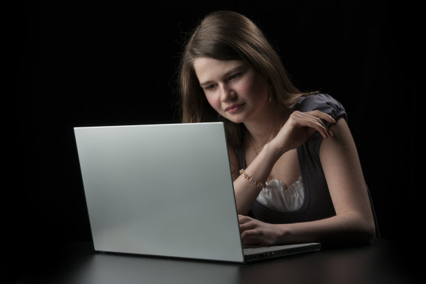 一头棕色长发的年轻女孩向手提电脑走来图片下载