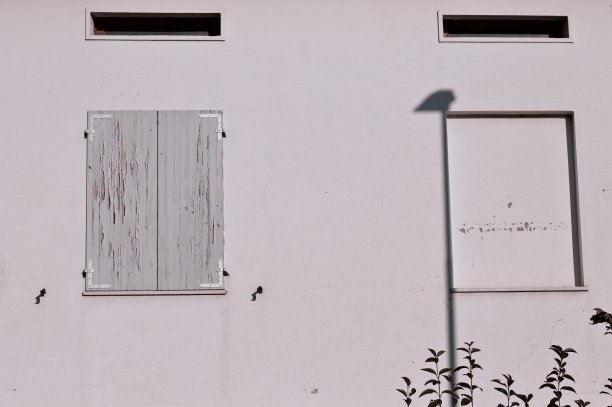 白色墙壁上的两扇窗户，木制百叶窗已经破损(意大利，Pesaro，欧洲)图片下载