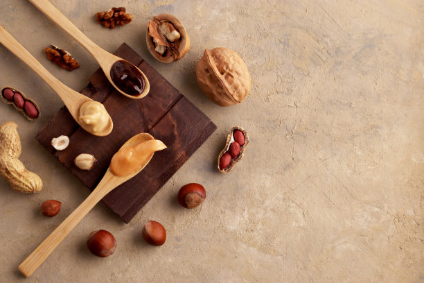 黄油，坚果酱，用木勺和配料放在浅色的背景上。自制生有机榛子，花生，核桃。天然和素食产品的概念。顶视图,flatlay。副本的空间。图片下载