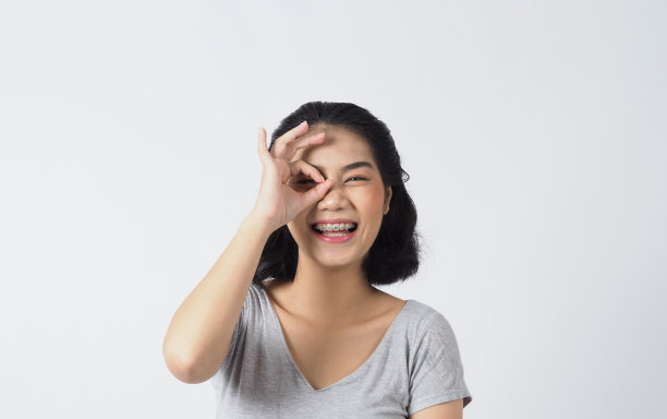 口腔护理。牙架少女微笑着看着镜头。白色的牙齿和蓝色的牙套。牙科保健。亚洲女性，戴隐形眼镜和牙齿矫正配件。美容手术。白色BG图片下载