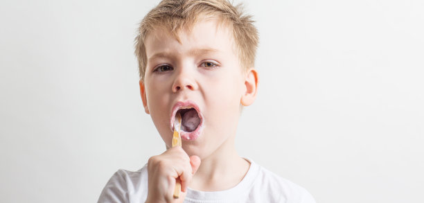 可爱的小男孩嘴里叼着竹牙刷，孩子在刷牙图片下载