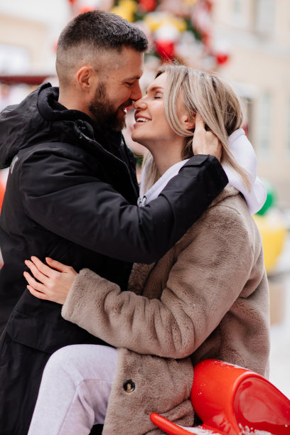 男人和女人在灯光下的街道上摆姿势拍摄冬天的照片。散景图片下载