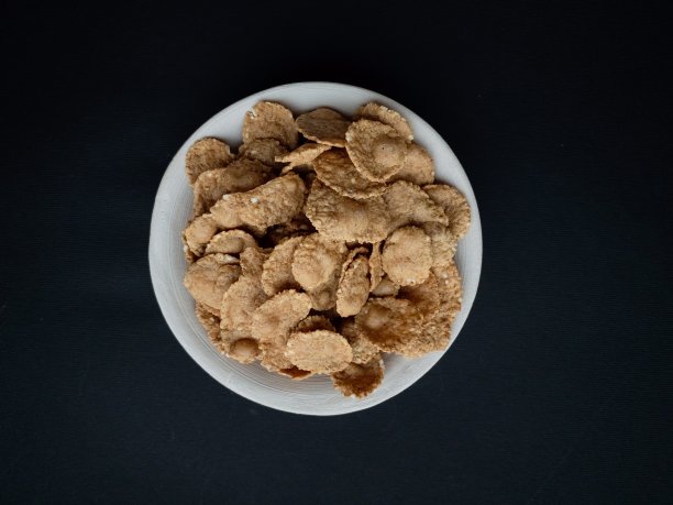 早餐谷物，在美丽的黑色背景上的黏土盘子里的杂粮片。食品的概念。图片下载