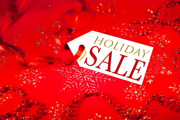 在圣诞节和新年假期期间，在装饰过的圣诞背景上贴上印有假日销售字样的标签。图片下载