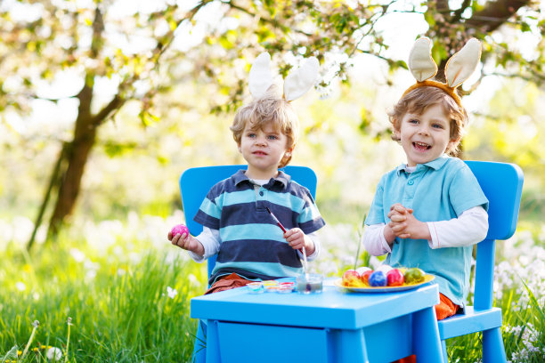 两个小男孩戴着复活节兔子耳朵，画着五颜六色的彩蛋图片下载