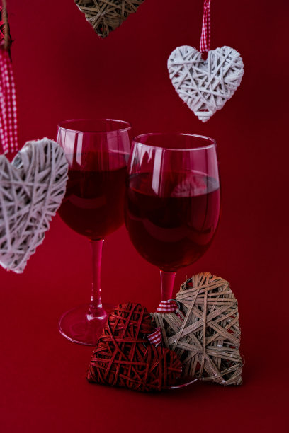 两杯红酒和装饰心。爱浪漫。夫妇关系。红色哑光背景。白色和红色元素。情人节浪漫晚餐图片下载