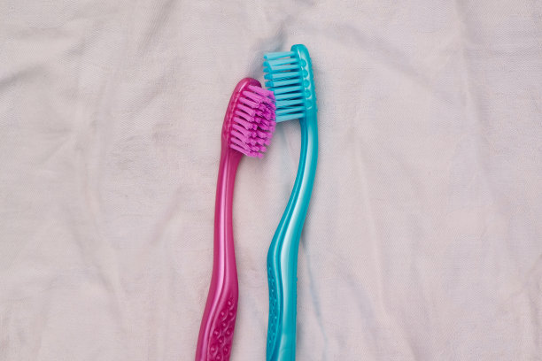 两支牙刷放在凌乱的床单上，性爱和亲密的想法。图片下载