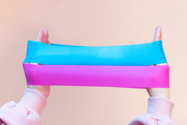 女孩拿着两个健身牙龈，粉红色背景上的扩张器，正面视图图片下载