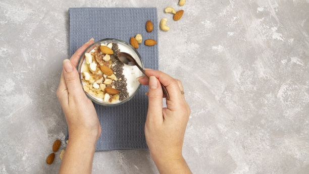 女孩拿起一把勺子，用酸奶、水果、坚果和种子做的奇亚冰沙。适当营养的概念。健康的早餐。图片下载