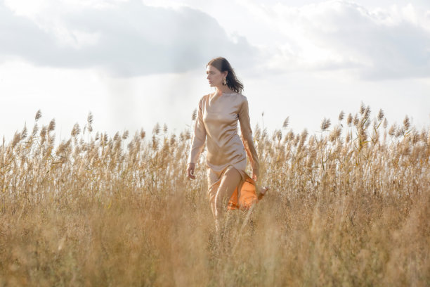 时尚的户外肖像女人在米色丝绸缎长连衣裙。图片下载