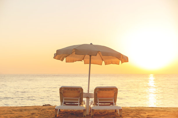 米色棉布沙滩伞，海边有两个日光浴床图片下载