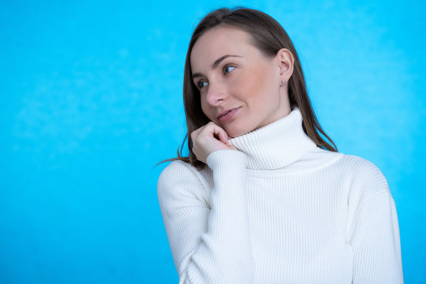 性感漂亮的女人黑发穿休闲潮流衣服约会走白色毛衣在蓝色的背景图片下载