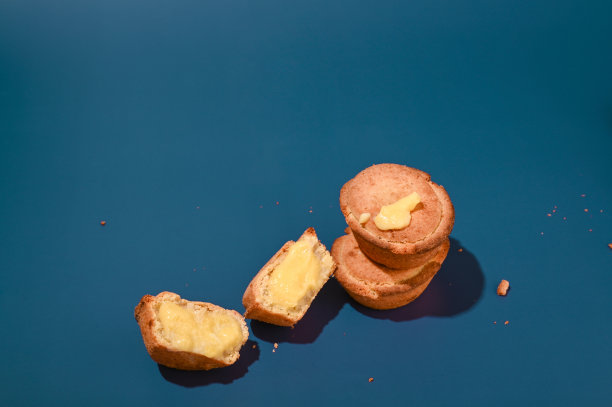 Pasticciotti。来自意大利南部阿普利亚地区的典型糕点。蓝色背景上有奶油的圆面包。强光，时尚摄影潮流。高质量的照片图片下载