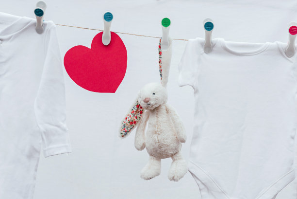 洗过的白色婴儿衣服、玩具和用塑料别针挂在晾衣绳上的红心。图片下载