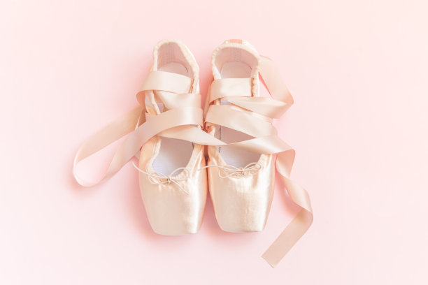 新的粉彩米色芭蕾舞鞋与缎带孤立在粉红色的背景。用于舞蹈训练的芭蕾舞经典尖头鞋。芭蕾舞学校的概念。俯视图平放，复制空间图片下载