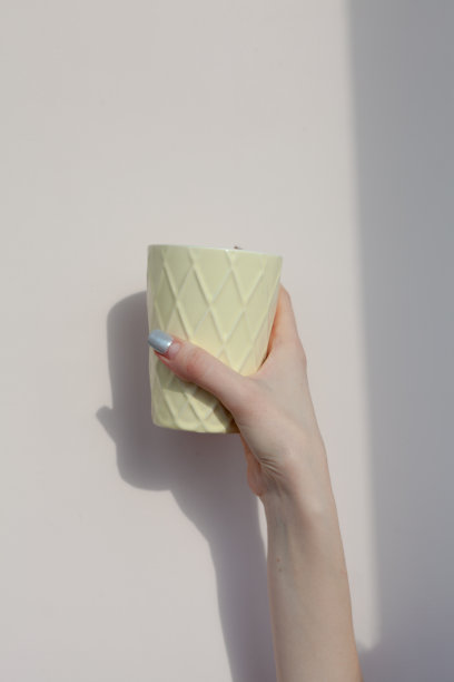 一个女人的手拿着一个白色背景上的杯子图片下载