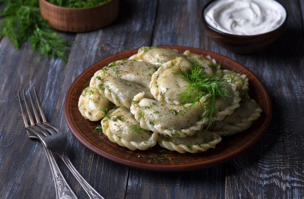自制素食饺子，vareniki, pierogi, kreplach，塞满了素食扁豆“肉”，胡萝卜和洋葱，放在木桌上，配上酸奶油和绿色蔬菜图片下载