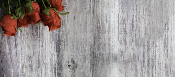 情人节概念俯视图。红玫瑰花和美丽的绿叶放在一张木桌上。特写照片和选择焦点，复制空间的右边的设计和文本。木头的背景图片下载