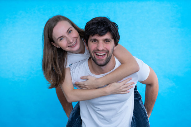 一对美丽的夫妇正在玩，而一个男人抱着他的女朋友孤立在一个蓝色的背景图片下载